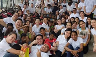 A large group of people posing together indoors, many wearing white shirts.