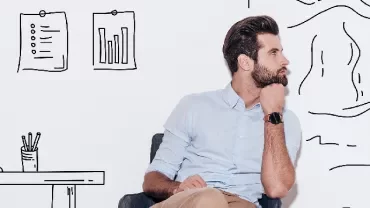 Man sitting in front of wall with doodles of office space and mountains.